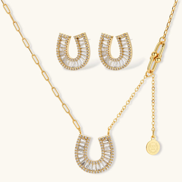 Sparkling horseshoe-shaped jewelry set with AAA cubic zirconia in gold-plated and white gold finishes on cream background.