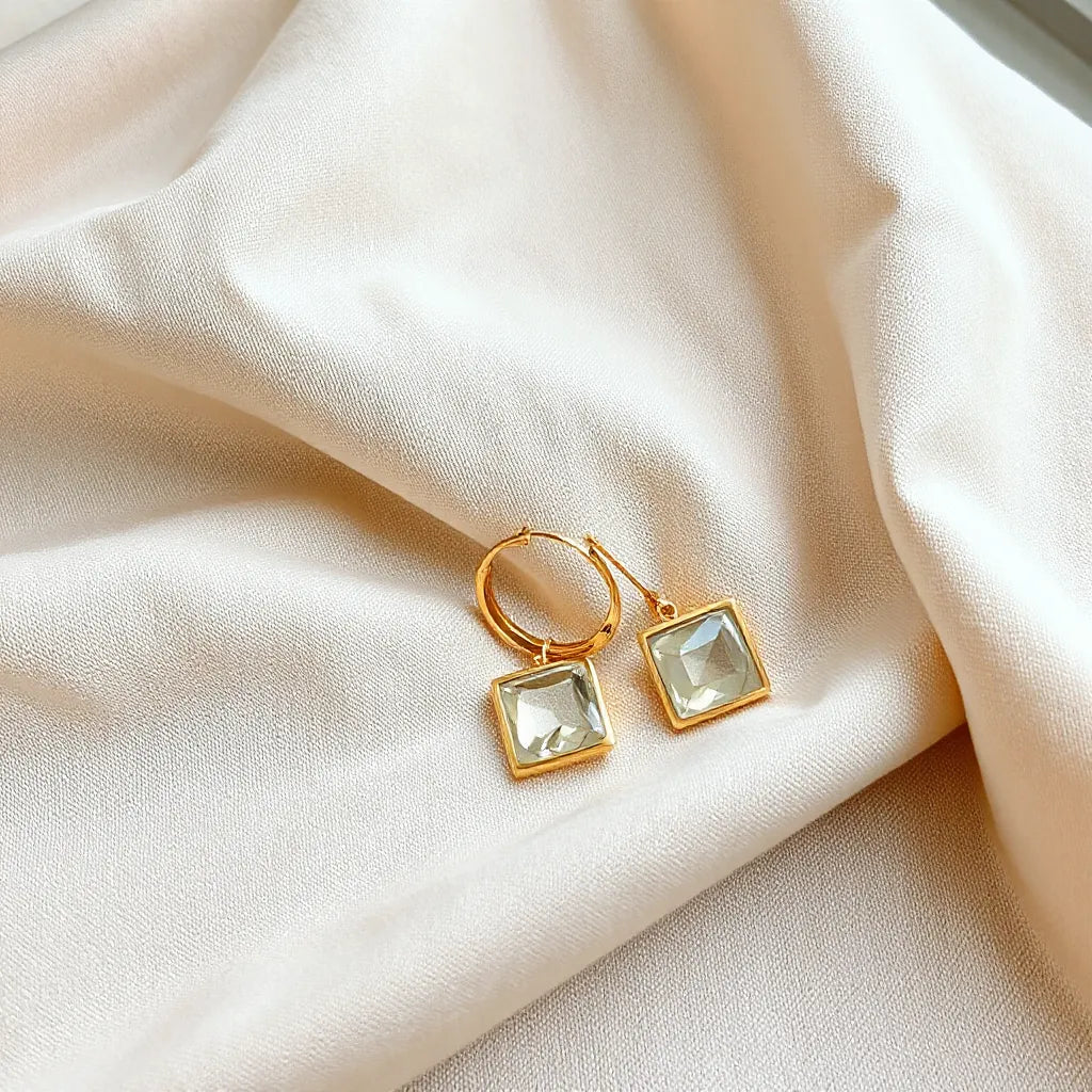 Geometric bracelet and matching earrings with polished facets on a neutral fabric background