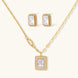 Gold-plated jewelry set with rectangular cubic zirconia stones in pave halo settings on cream background