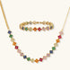 Colorful four-leaf clover jewelry set with rainbow cubic zirconia stones in gold-plated setting on white background