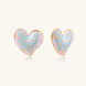 Heart-shaped stud earrings with swirled turquoise and pink enamel in gold-plated frames on cream background