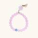 Stretchy beaded bracelet with pink rose quartz, blue aquamarine, carved floral pendant, and pearl tassel clasp.
