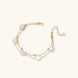 Double-strand gold bracelet with irregular baroque pearls and smooth freshwater pearls on cream background.