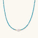 Delicate gold vermeil necklace with teal apatite beads and freshwater pearl on white background.