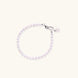 Adjustable bracelet featuring lustrous freshwater pearls with rhodium-plated sterling silver clasp on cream background.