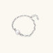 Rhodium-plated silver chain bracelet with single white freshwater pearl and heart charm clasp on cream background