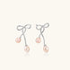 Rhodium-plated silver earrings with organic vine curves and two peachy freshwater pearls on cream background
