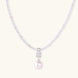 Dainty necklace with lavender crystal beads, freshwater pearls, geometric pendant, and large pearl drop on white background.