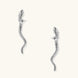 Silver-toned serpent-shaped dangle earrings with detailed scale texture curving in S-shape on beige background