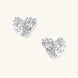 Pair of sculptural white gold-plated stud earrings with twisted ribbon design and sparkling zirconia stones on cream background