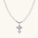 White pearl necklace with ornate silver cross pendant featuring zirconia crystals on cream background.