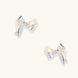Dimensional bow stud earrings in white gold plated brass with silver and cream two-tone finish on neutral background