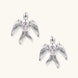 White gold-plated bird earrings with spread wings and oval zirconia center on cream background