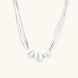 Sterling silver multi-strand necklace with three brushed round beads on cream background