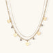 Gold layered necklace set with engraved heart pendants and crystal accents on cream background