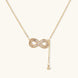 Gold infinity pendant with baguette crystals on adjustable chain against cream background.