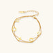 Double-layer gold-plated bracelet with quatrefoil and star charms on cream background, 18K gold finish.