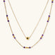 Two layered gold-tone necklaces with purple stone beads and star pendant against cream background.
