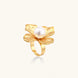 Gold-plated flower ring with textured petals and white cotton pearl center on cream background